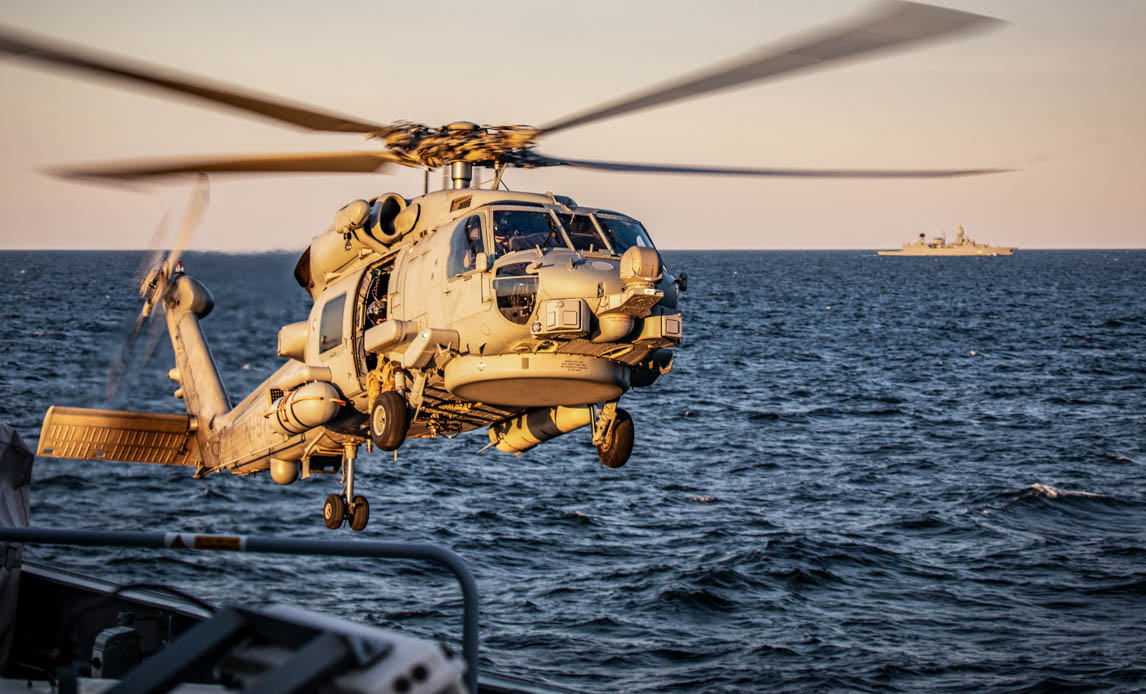 Helikopter i forgrunden og bagved et dansk krigsskib