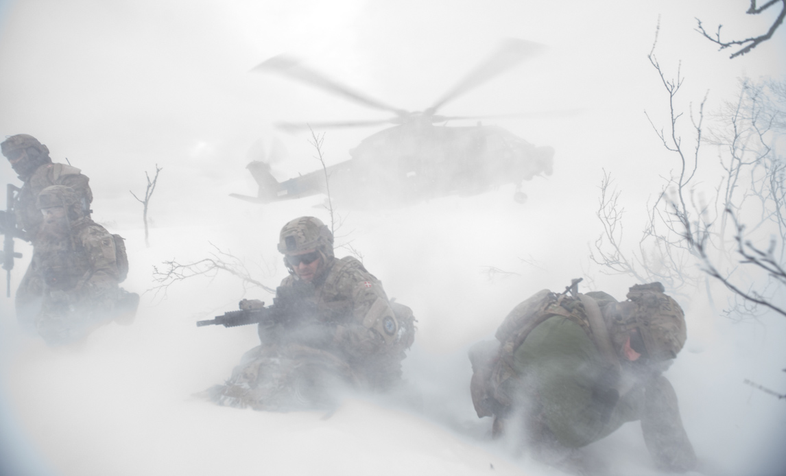 Soldater i sne med helikopter i baggrunden