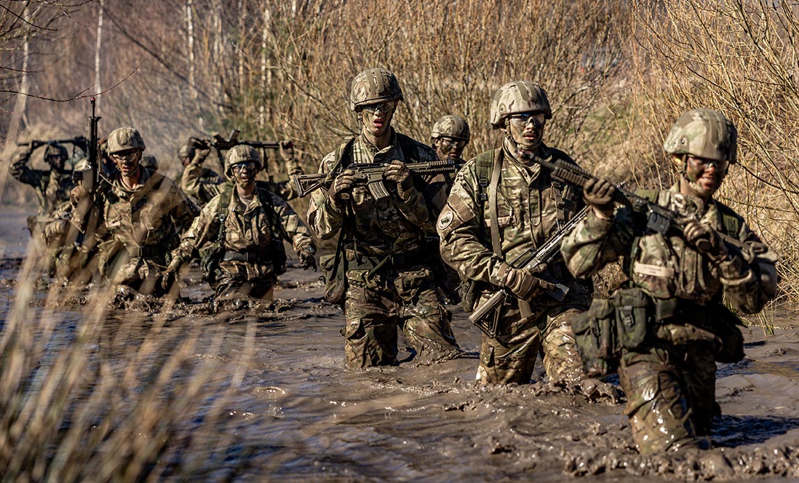 Værnepligtige går gennem et større vandløb