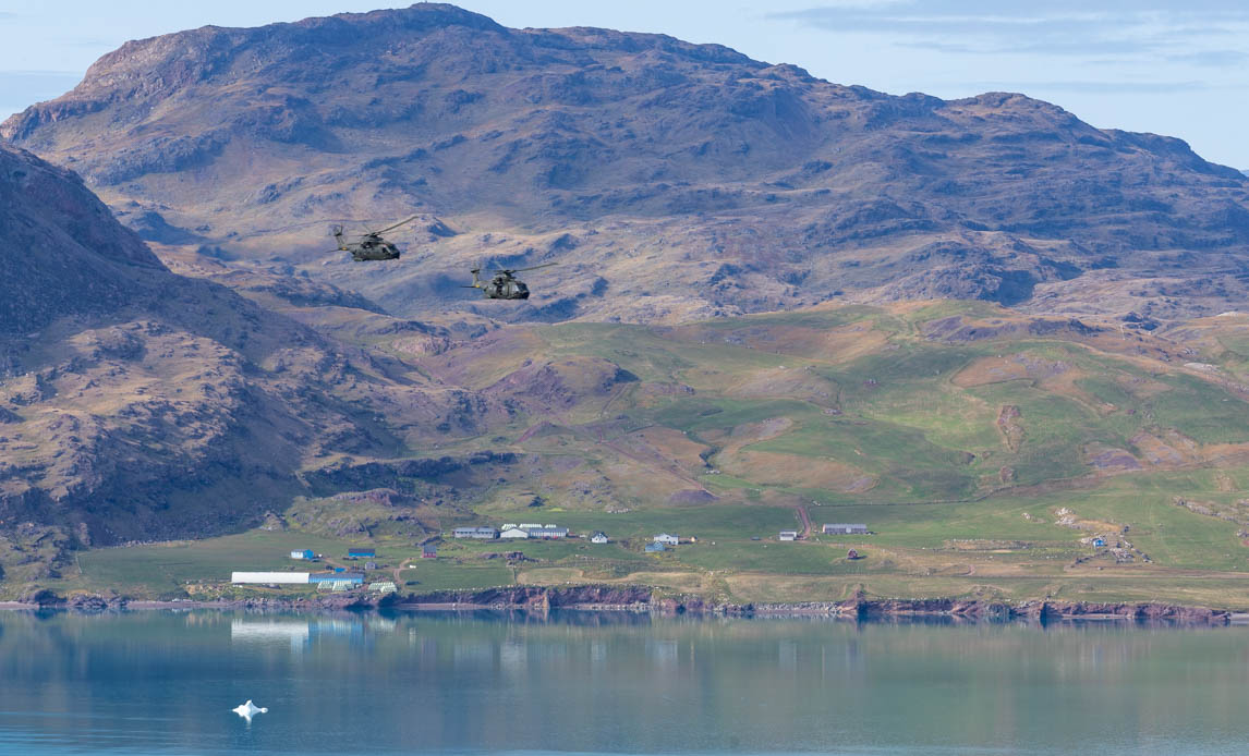 2 eh101 helikoptere flyver over grønlandsk landskab