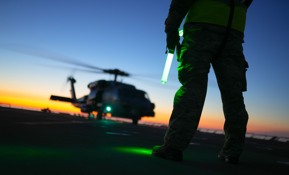 Helikopter på skibsdæk i solnedgang