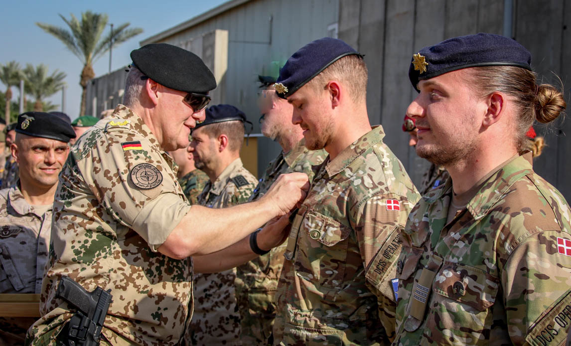 En tysk brigadegeneral overrækker medaljer til to operatører fra det danske kommunikationsmodul.
