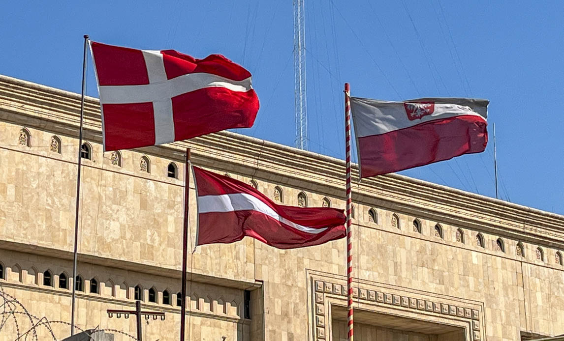 Det danske, lettiske og polske flag vajer over det danske sikrings- og eskortekompagnis område i Union III.