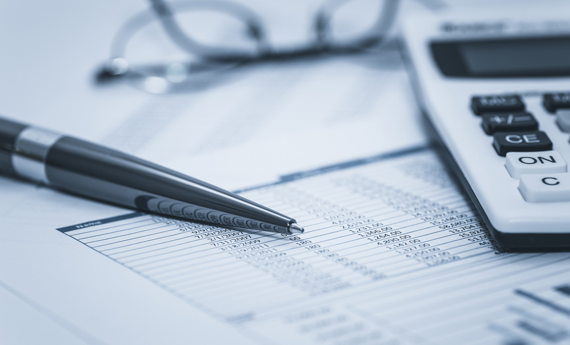 Nærbillede af en rapport med tal. På billedet ses også en sort kuglepen, en lommeregner og et par briller