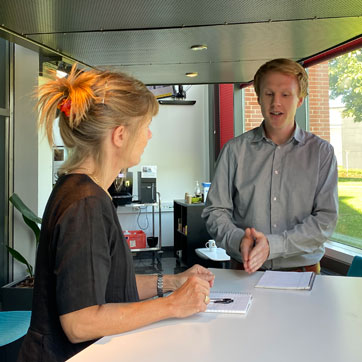 En kvindelig og mandlig medarbejder står ved et højt bord og snakker