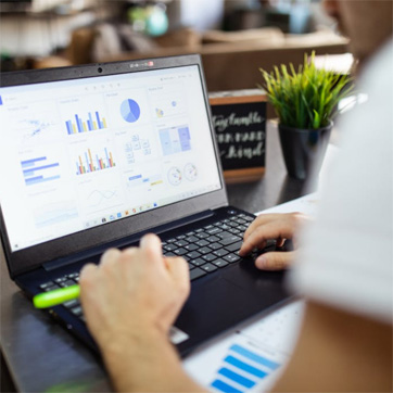 En person arbejder foran en bærbar computer. På skærmen kan ses en række diagrammer og anden data.